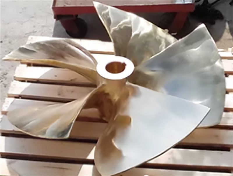 Hélice naval de bronce de cuatro aspas sobre una tarima de madera