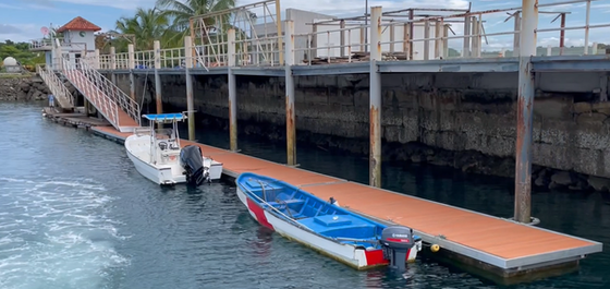 Muelle flotante con cubierta de madera plástica y embarcaciones atracadas
