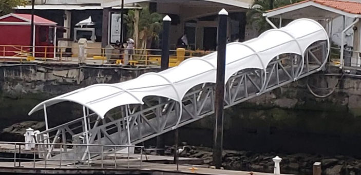 Pasarela de aluminio cubierta con velaria blanca sobre el agua